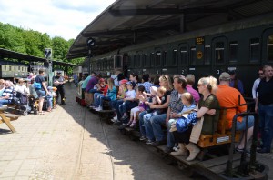 Ein vollbesetzter Feldbahnzug kommt aus dem Wald zurück